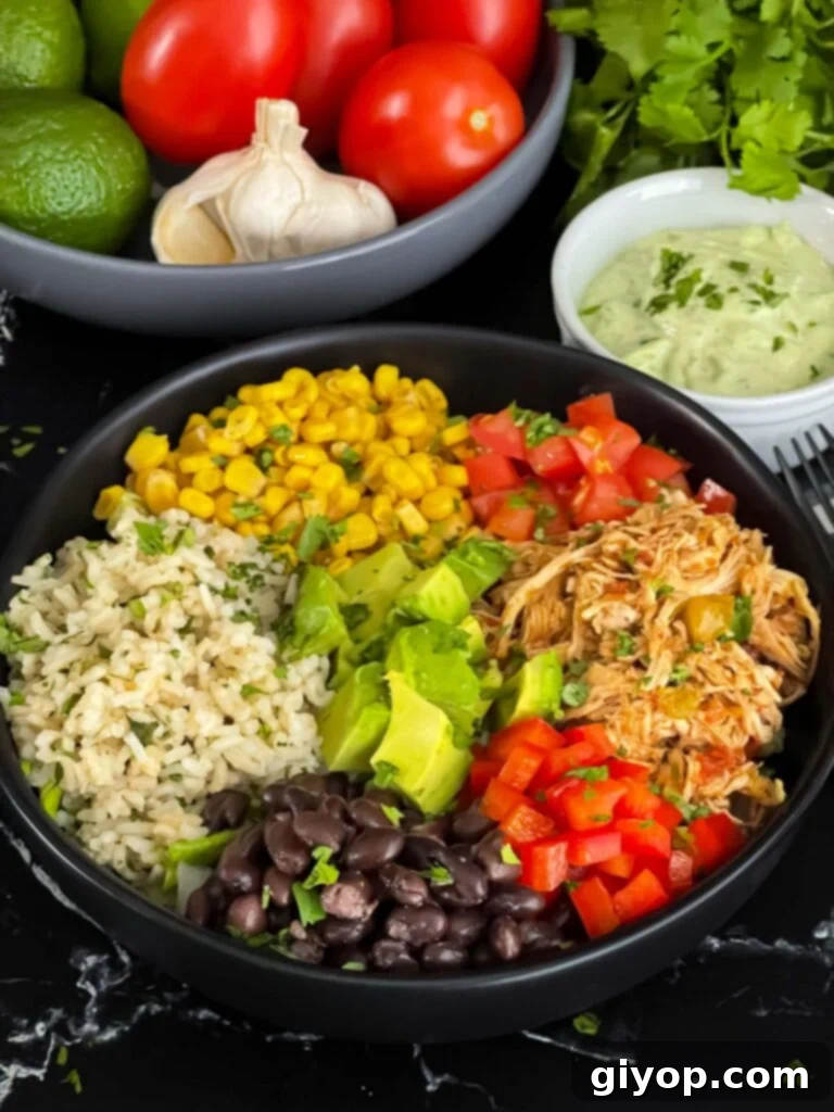 A perfectly assembled chicken burrito bowl, glistening with creamy avocado sauce, beautifully presented against a dark, inviting background.