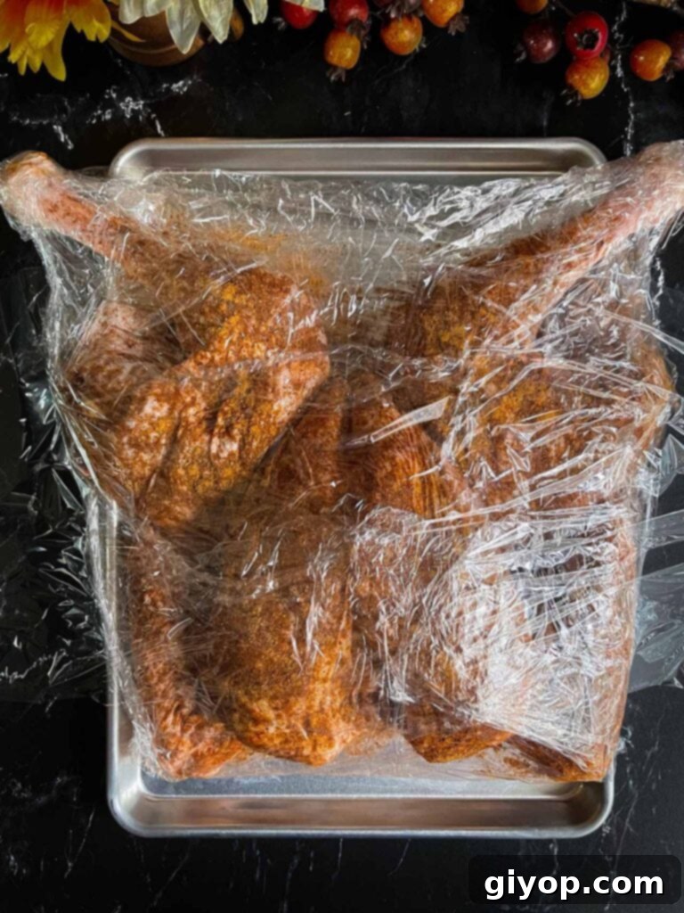 Ultimate Dry Brined Spatchcock Turkey 11 A dry brined raw turkey wrapped in plastic wrap.