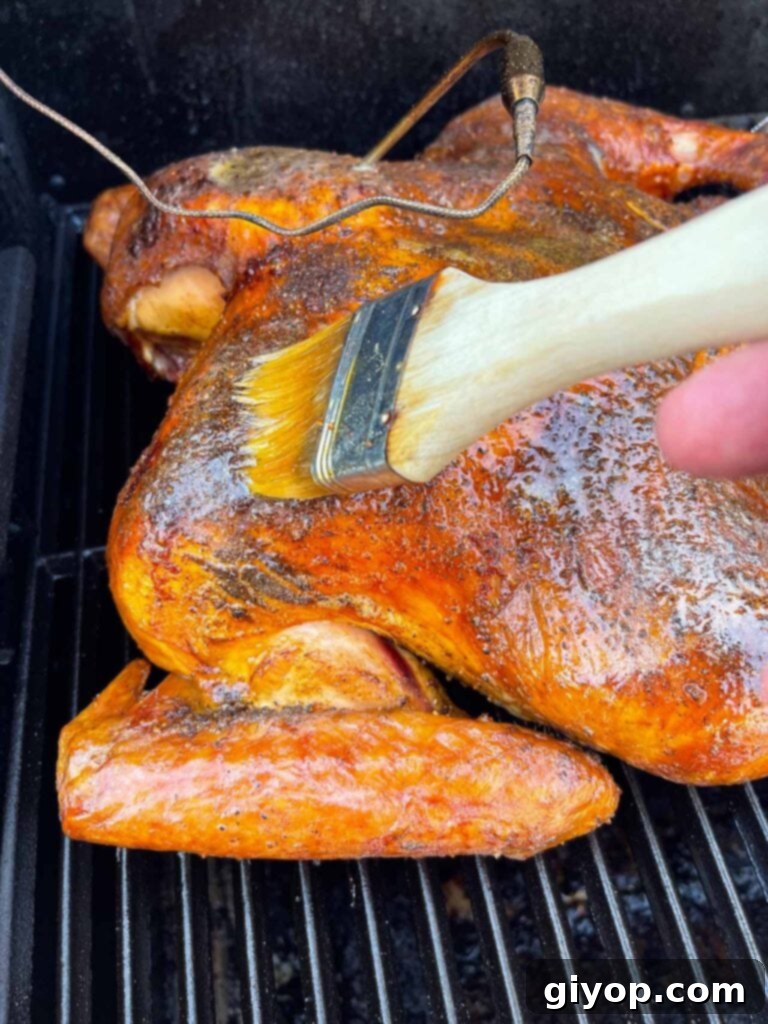 Ultimate Dry Brined Spatchcock Turkey 15 brushing butter over a roasting turkey on the Masterbuilt.