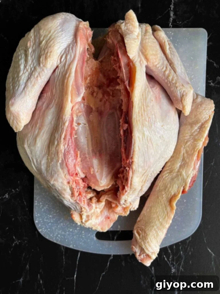 Ultimate Dry Brined Spatchcock Turkey 8 A turkey with its backbone removed on a white cutting board.