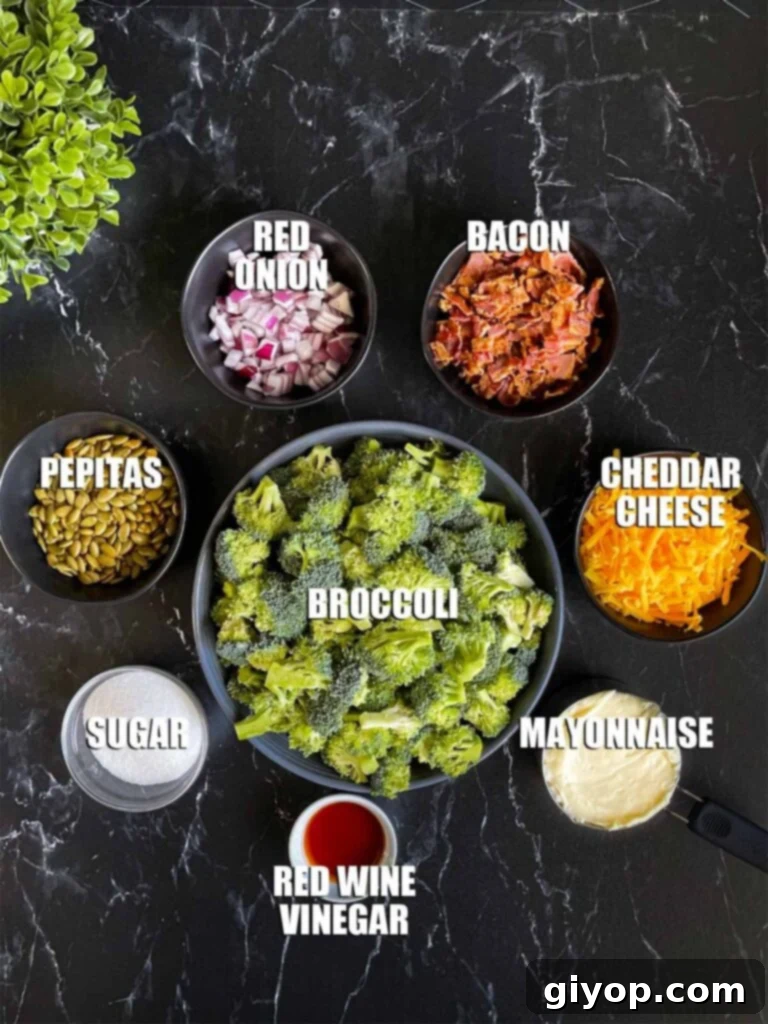 A selection of fresh broccoli salad ingredients, including broccoli florets, bacon, red onion, and cheese, neatly arranged on a dark countertop.