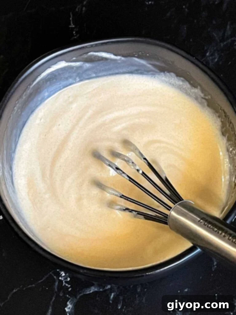 A small dark bowl holds the creamy broccoli salad dressing, perfectly mixed and ready to be poured.