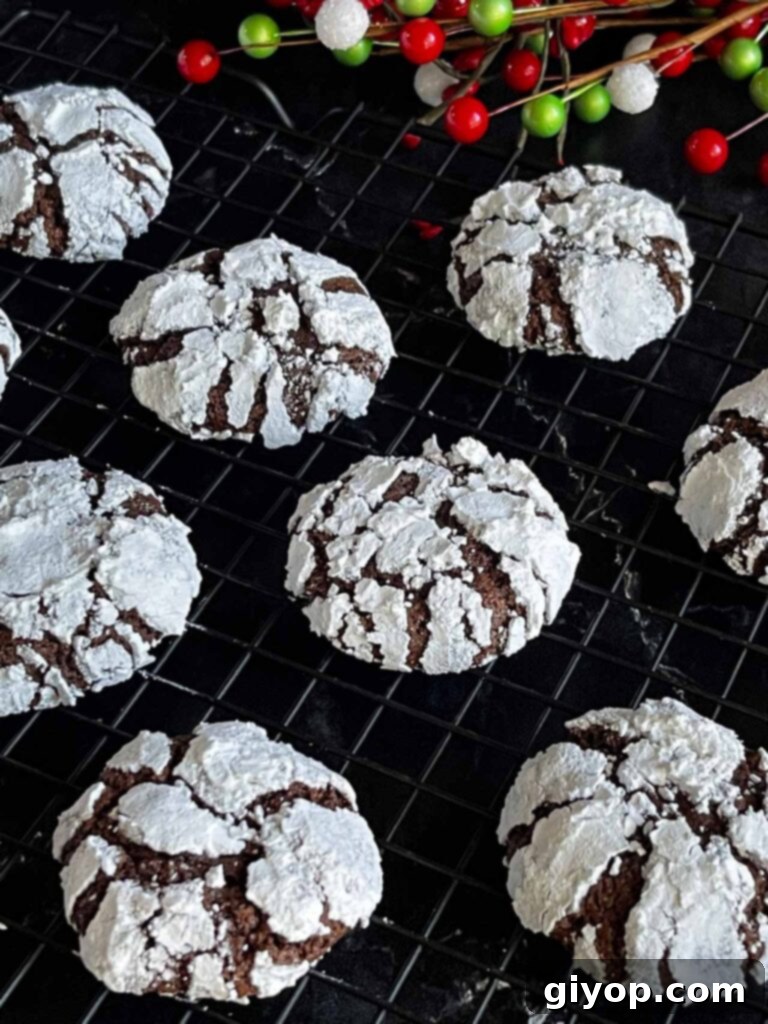 Freshly baked chocolate crinkle cookies cooling on a wire rack, showcasing their signature cracked powdered sugar coating.
