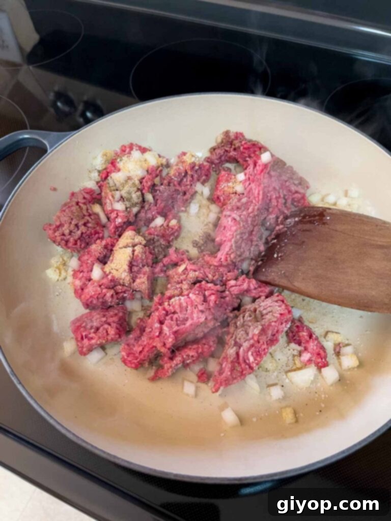 Beef and onions cooking in a cast iron skillet.
