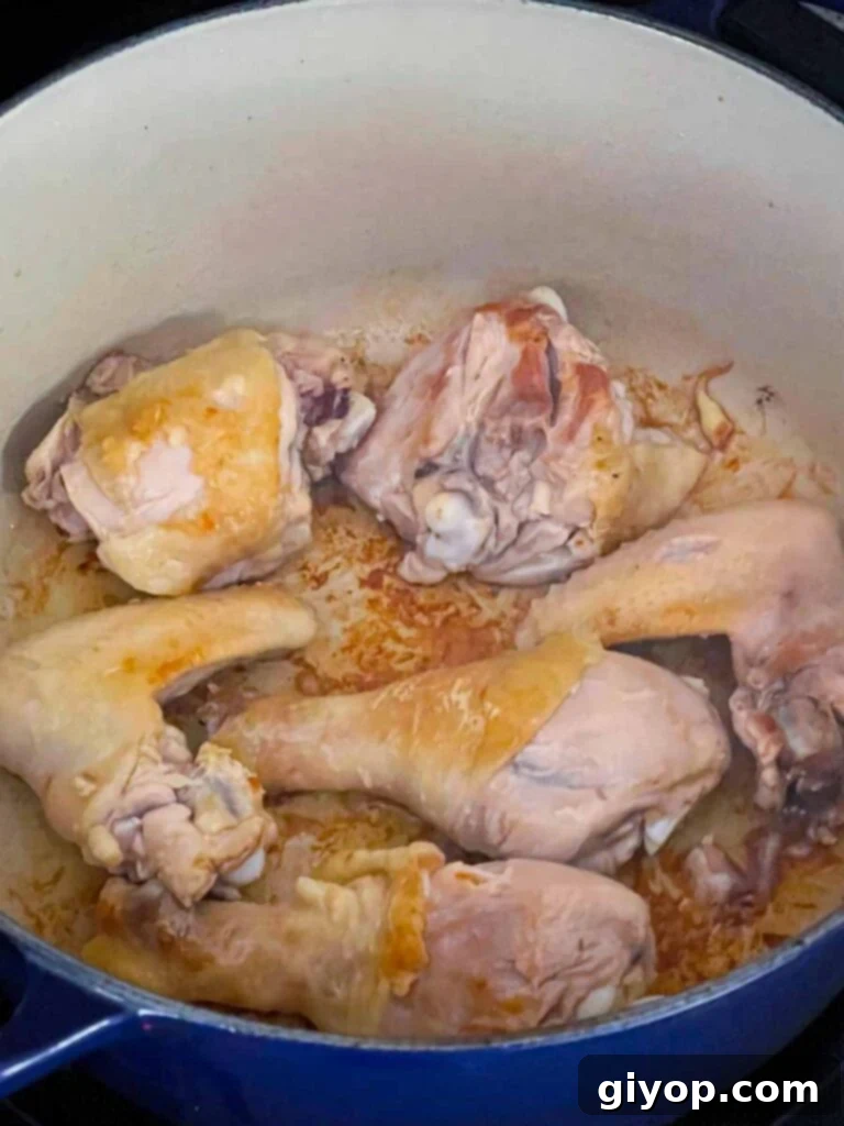 Chicken quarters being browned to perfection in a large Dutch oven, creating rich flavor for the stock.