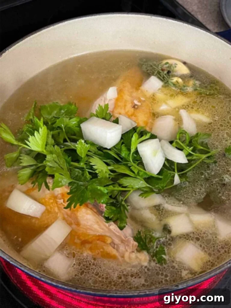 Homemade chicken stock simmering gently in a Dutch oven with chicken and fresh vegetables, creating a rich base.