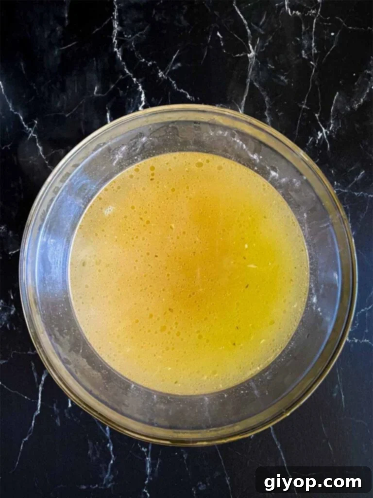 Golden homemade chicken stock, free of impurities, poured into a clear glass bowl, ready for the next step.