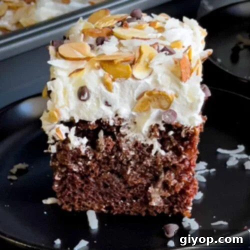 Slice of Almond Joy cake on a dark plate.