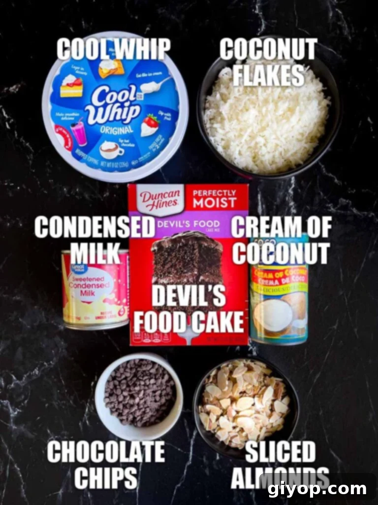 Almond Joy cake ingredients laid out on a dark background, including a box of cake mix, cans of milk, shredded coconut, almonds, and chocolate chips.