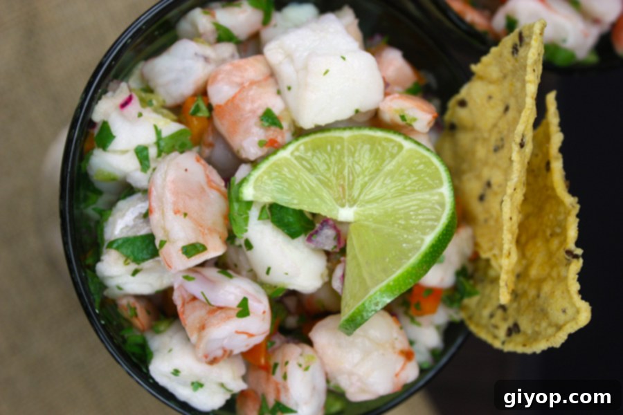 Ceviche in two green margarita glasses garnished with a lime slice and tortilla chips.