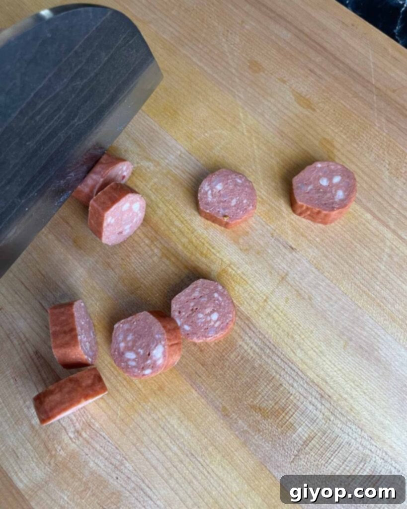 Pitmaster's Piggy Poppers 5 Cutting smoked sausage on a cutting board.