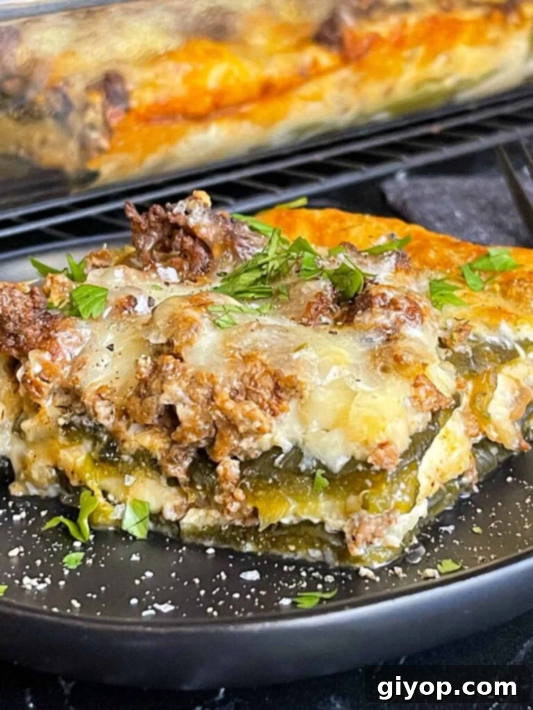 Cheesy Chile Relleno Bake 2 A serving of chile relleno casserole on a dark plate with the casserole in the background.