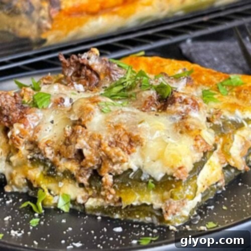 Cheesy Chile Relleno Bake 15 A serving of chile relleno casserole on a dark plate with the casserole in the background.