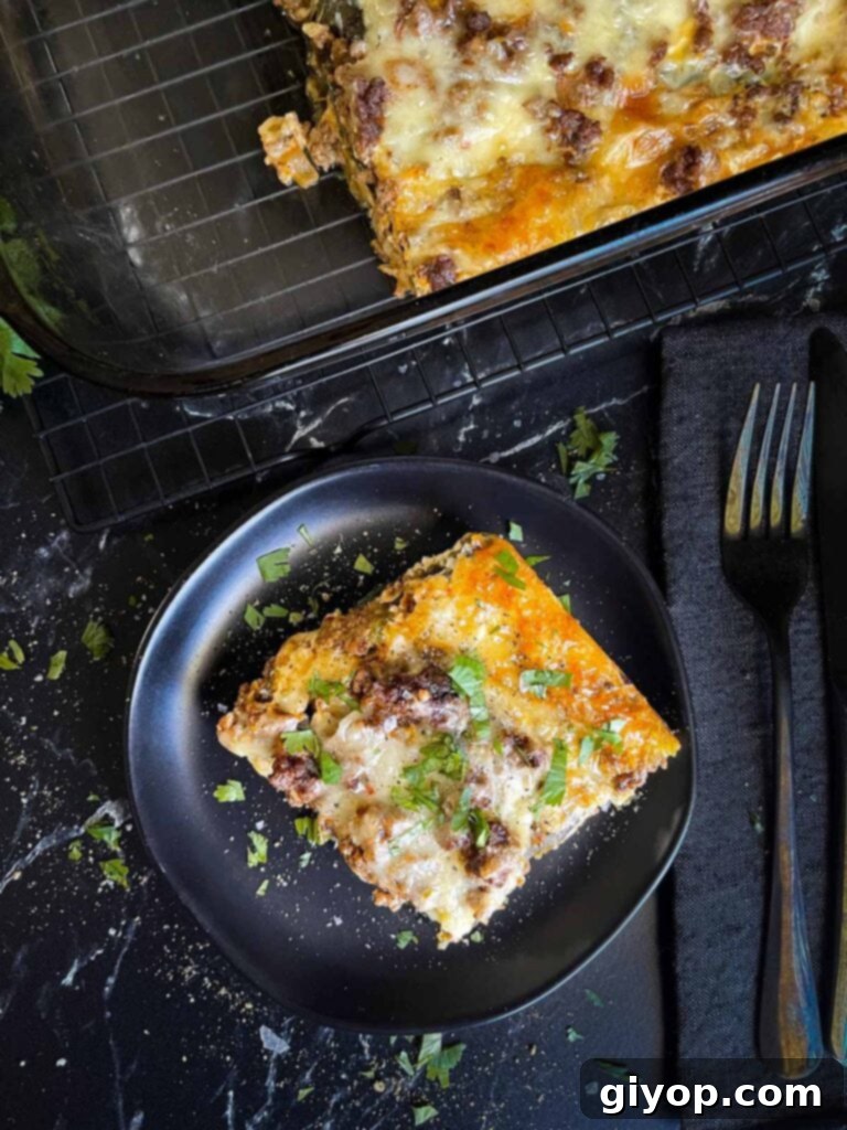 Cheesy Chile Relleno Bake 3 A serving of chile relleno casserole on a dark plate with the casserole in the background.