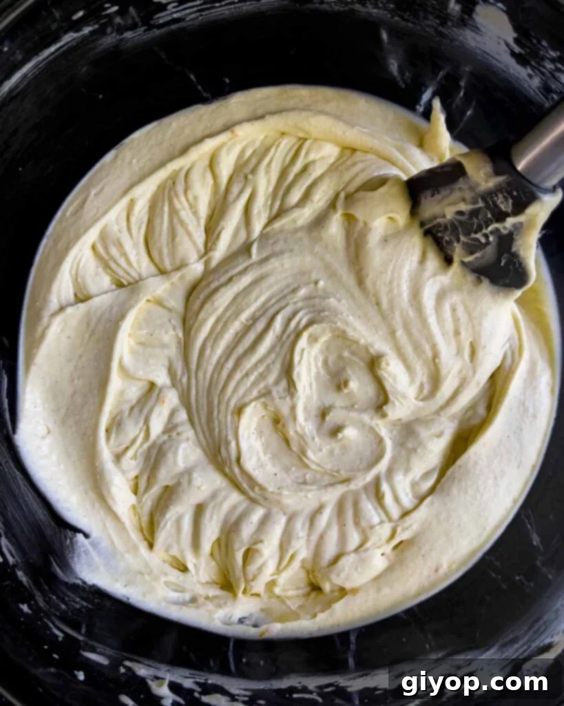 The fully mixed, smooth, and creamy cannoli cheesecake batter resting in a clear glass bowl, ready for chocolate chips and baking.