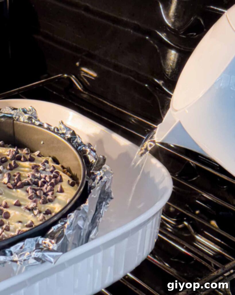Boiling water being carefully poured into the roasting pan around the cannoli cheesecake while it's already in the oven, creating a water bath.