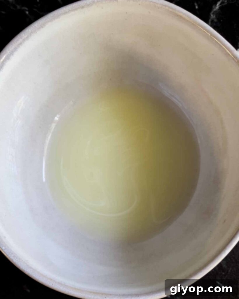 The liquid that was drained from the ricotta cheese, accumulated in the bottom bowl beneath the strainer.