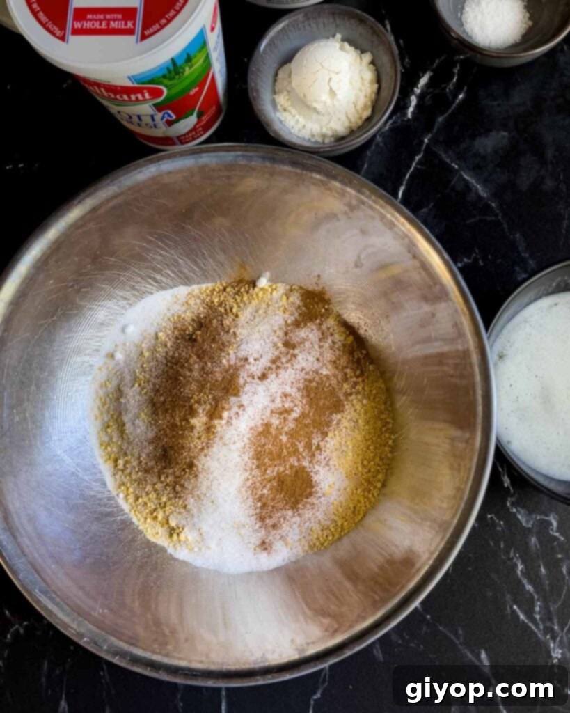 Graham cracker crust ingredients, including crumbs, cinnamon, salt, and melted butter, neatly arranged in a metal bowl before mixing.