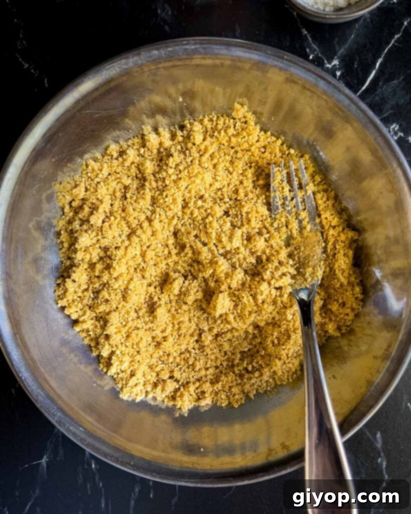 Crust ingredients thoroughly mixed together in a metal bowl, forming a cohesive, sandy mixture, ready to be pressed into the pan.