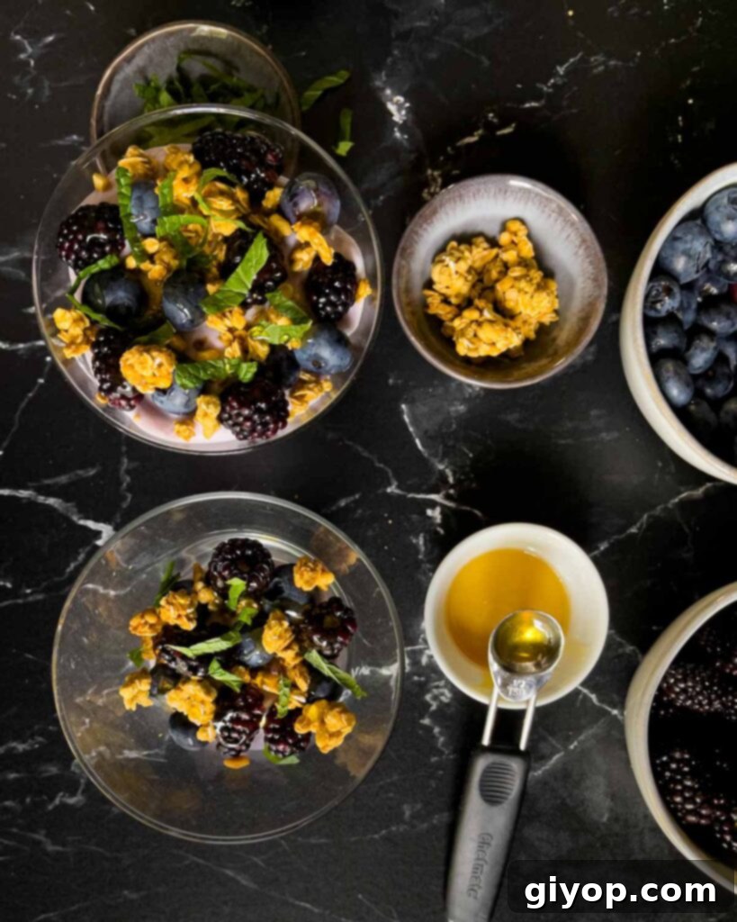 First layer of the berry yogurt parfait in a stemless martini glass on a dark surface.