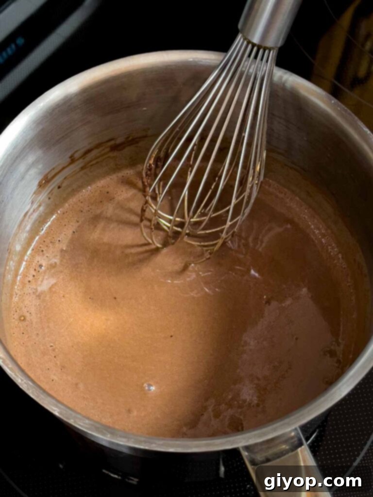 Chocolate frosting for the Mississippi Mud Cake being cooked in a metal saucepan, simmering gently.