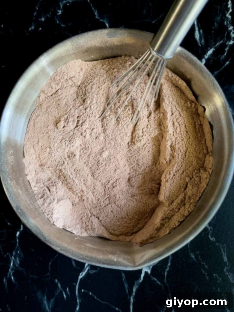 Dry ingredients for Mississippi Mud Cake whisked together in a metal bowl, creating a uniform mixture.