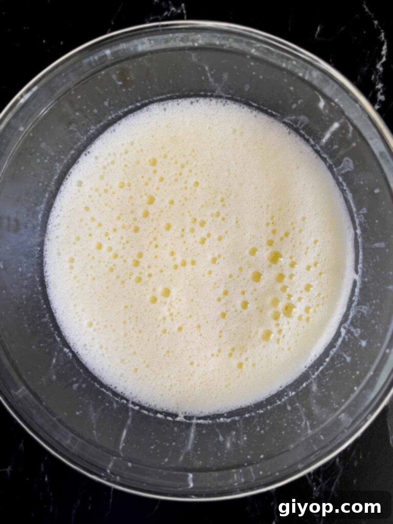 Wet ingredients for Mississippi Mud Cake being beaten vigorously in a glass bowl to incorporate air bubbles and create a light texture.