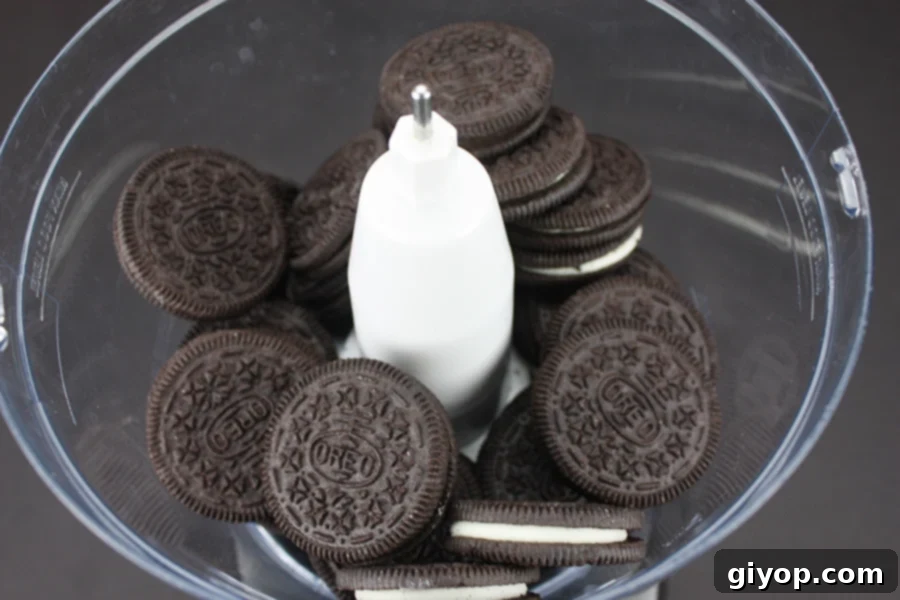 Whole Oreo cookies being added to the bowl of a food processor, ready to be crushed into fine crumbs for the pie's chocolate crust.