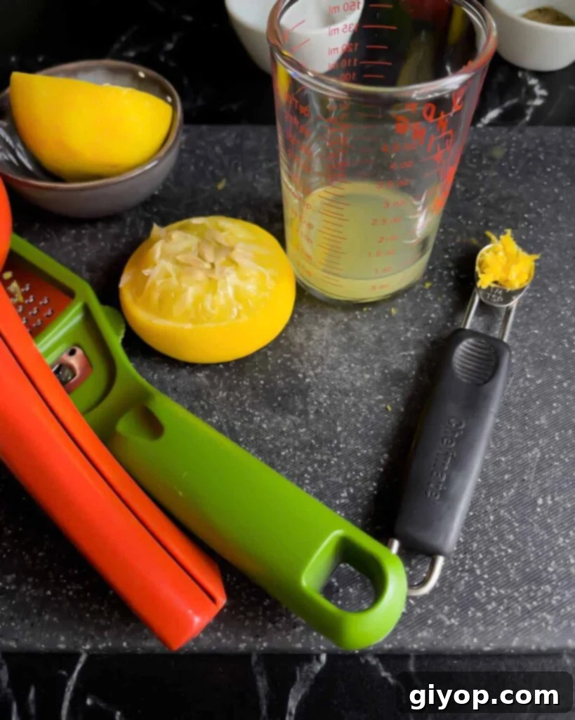 Juiced lemon and lemon zest for whipped feta on a dark cutting board.