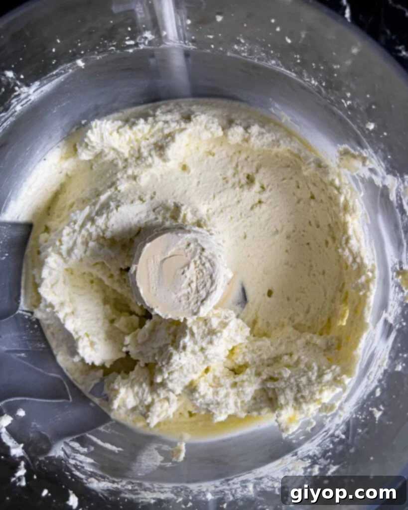 Whipped feta partially mixed in the bowl of a food processor.