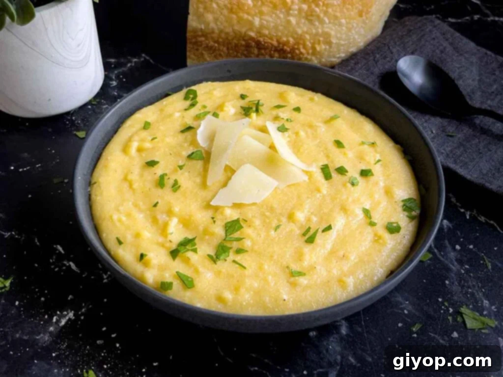 Effortless Creamy Polenta Perfection 2 Polenta in a dark bowl garnished with chopped parsley and parmesan cheese.