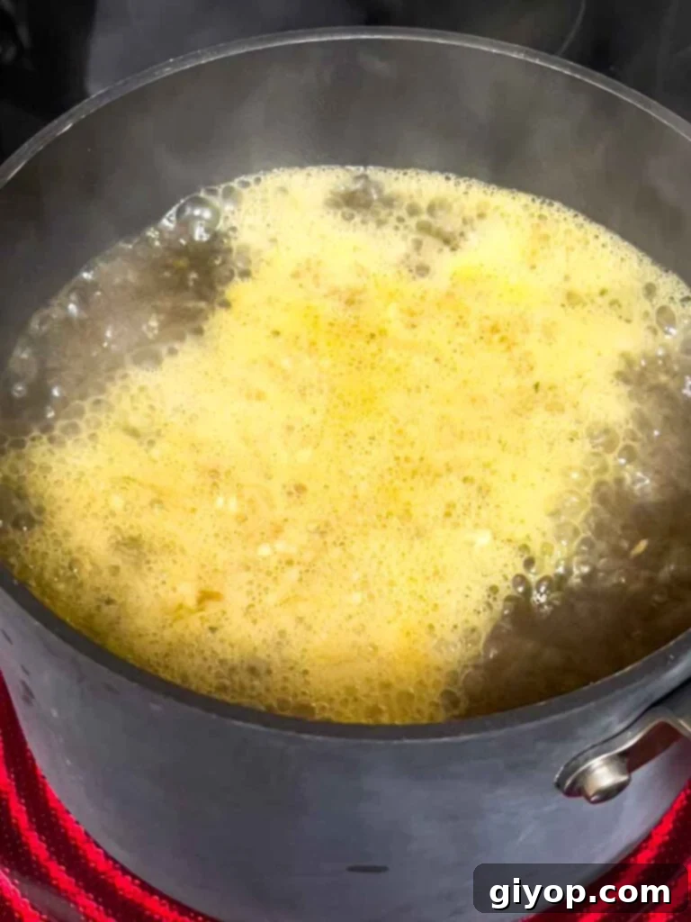 Effortless Creamy Polenta Perfection 6 Chicken stock boiling on the stovetop.