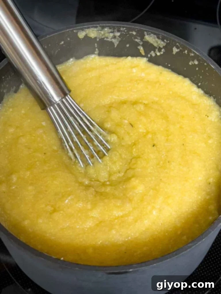 Effortless Creamy Polenta Perfection 7 Polenta cooking on the stovetop.