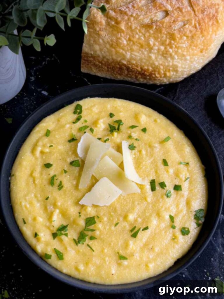 Effortless Creamy Polenta Perfection 10 Polenta in a dark bowl garnished with chopped parsley and parmesan cheese.