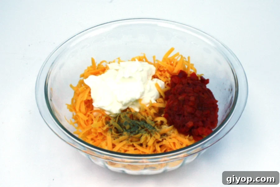 The Secret to Irresistible Homemade Pimento Cheese 4 Pimento Cheese ingredients in a glass mixing bowl, ready to be combined.