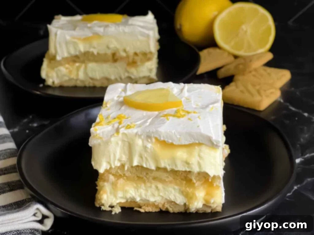 A stunning serving of No-Bake Lemon Icebox Cake, elegantly garnished with a fresh lemon slice and vibrant zest, presented on a dark plate, highlighting its creamy layers and refreshing appeal.