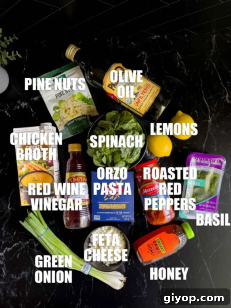 Assortment of fresh ingredients for Spinach and Feta Orzo Salad including spinach, feta, basil, and roasted red peppers, neatly arranged on a dark surface.