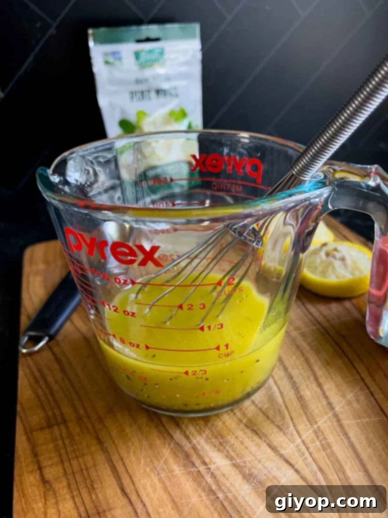 Ingredients for the vibrant lemon vinaigrette dressing, including olive oil, lemon, red wine vinegar, and honey, artfully arranged on a wooden cutting board.