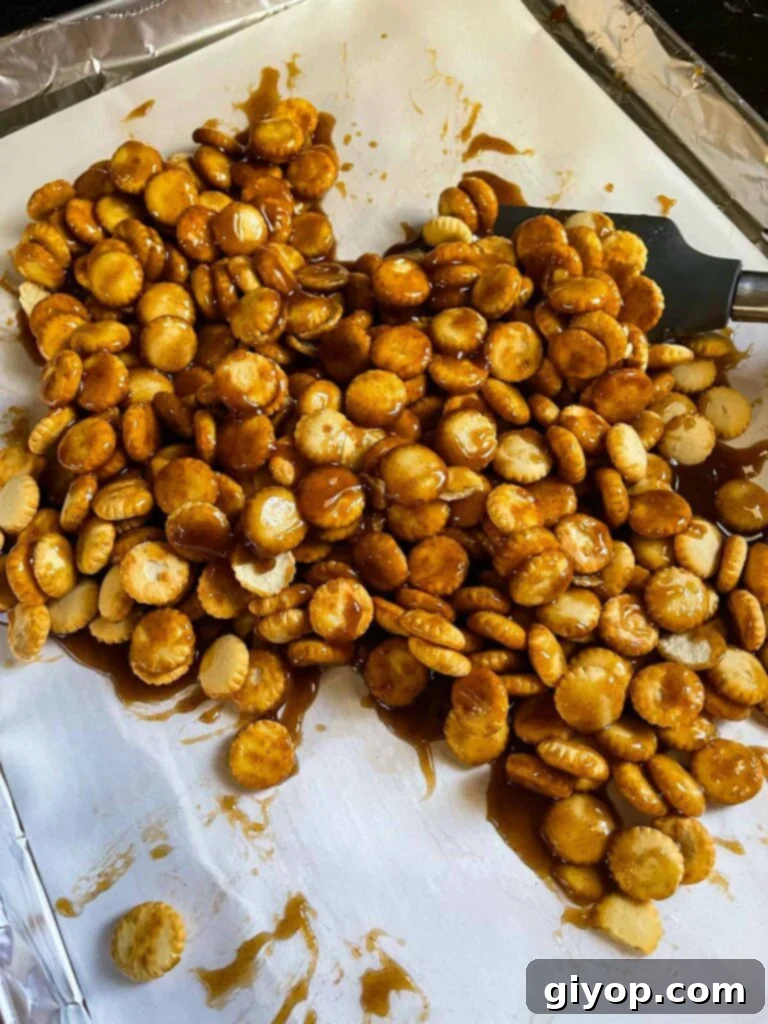 Toffee mixture evenly coating oyster crackers on a baking sheet.