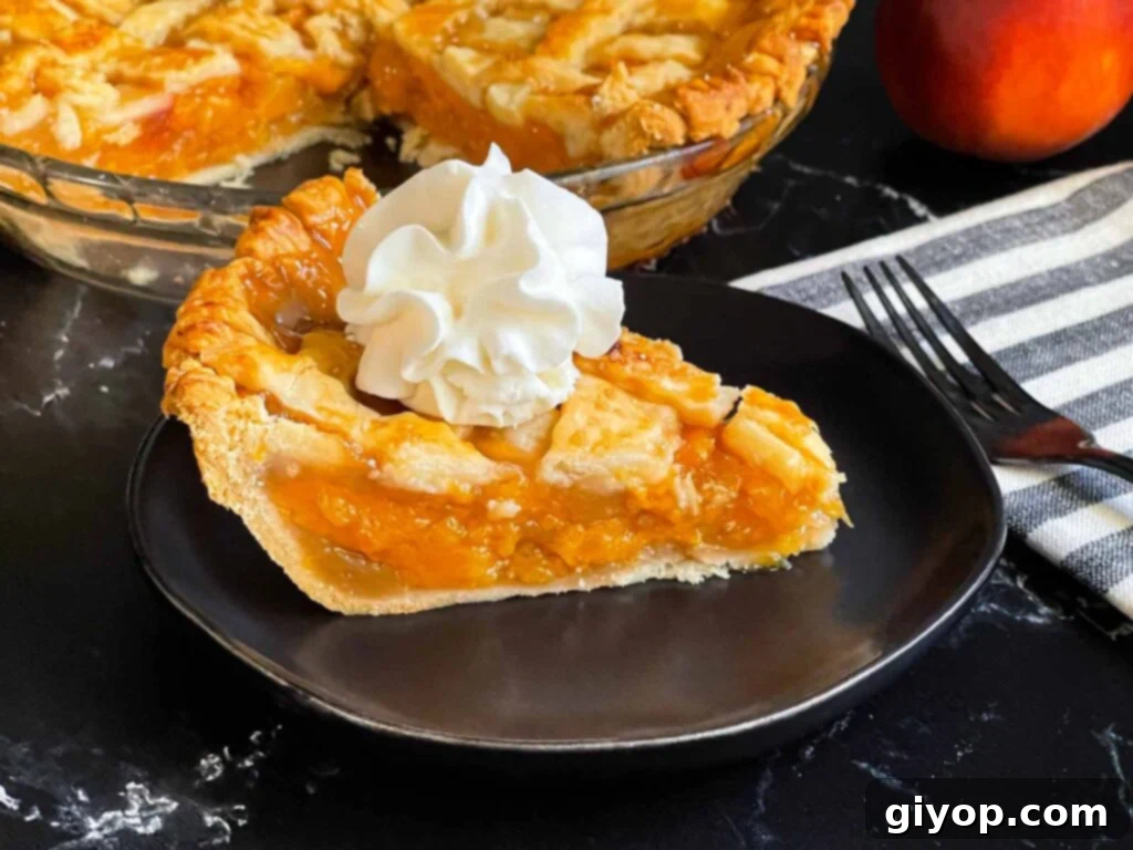 A beautifully presented slice of golden-crusted peach pie, topped with a dollop of fresh whipped cream, resting on an elegant dark plate.