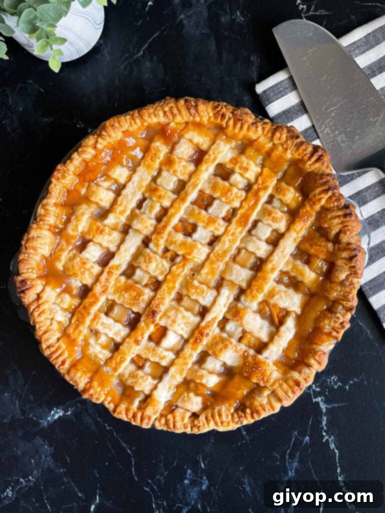 A perfectly baked peach pie with a golden-brown lattice crust, presented alongside a striped napkin and a pie slicer, ready to be served.