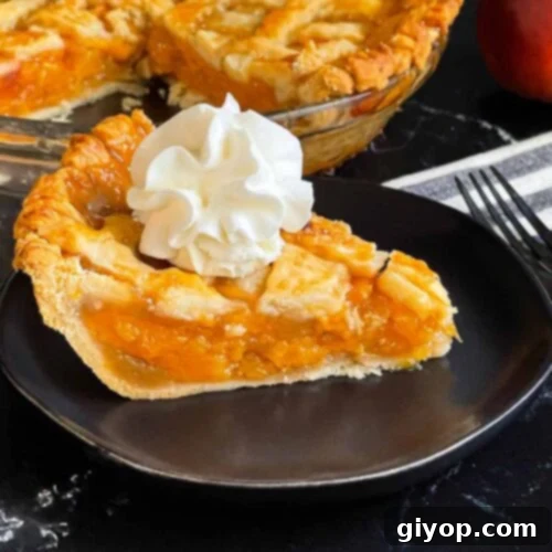 A slice of peach pie with whipped cream on a dark plate.