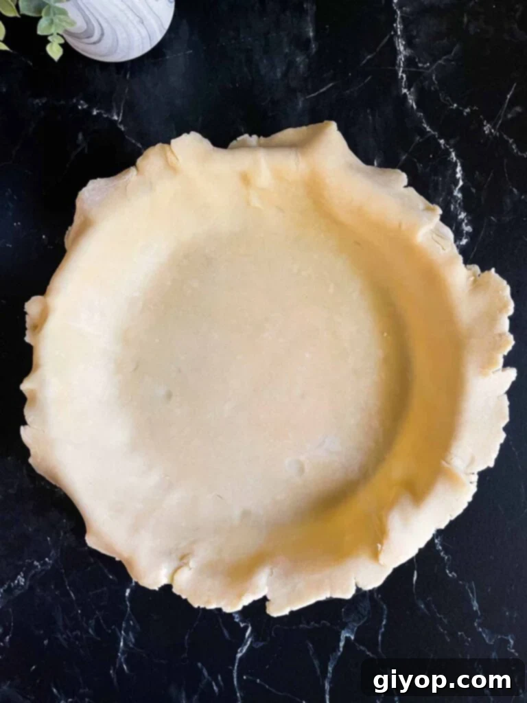 A pristine, unbaked pie crust expertly fitted into a glass pie baking dish, its edges ready for crimping or a lattice top.