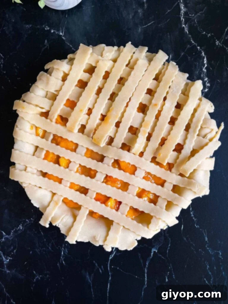 Skilled hands carefully weaving strips of pie dough into an intricate lattice pattern over a luscious peach filling in a baking dish.