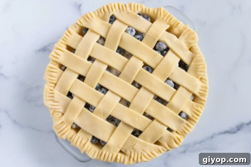 Perfectly Flaky Pie Crust 11 Unbaked blueberry pie with a beautiful lattice crust on a light surface.