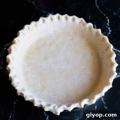 Perfectly Flaky Pie Crust 14 Fluted pie dough on a dark surface.