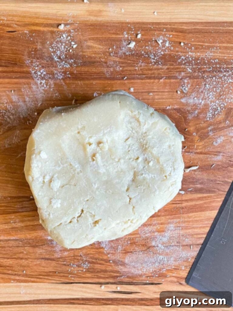 Perfectly Flaky Pie Crust 7 Pie crust dough gently gathered on a wooden cutting board.