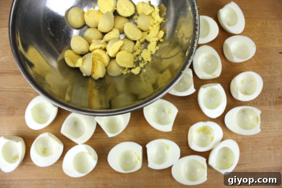 Deviled Eggs - egg yolks separated in a mixing bowl with the whites on a wooden cutting board, ready for filling.