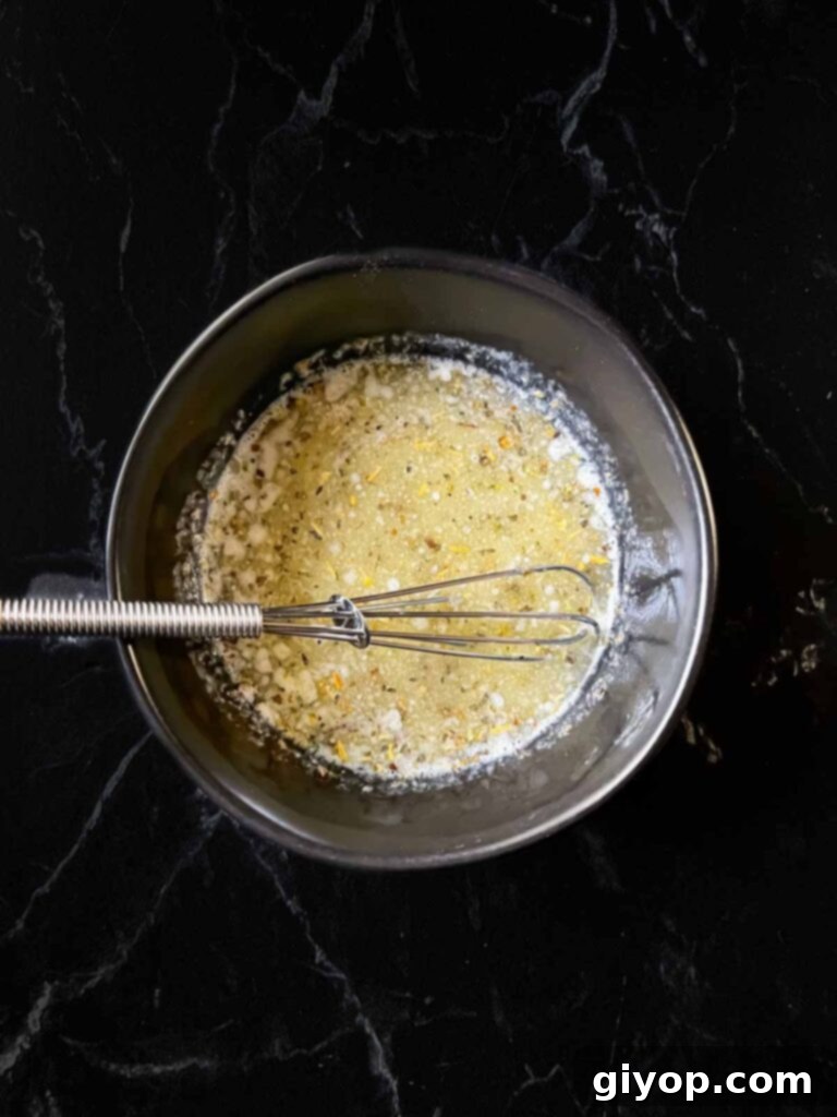 Cheesy Baked Chicken Parmesan Sliders 12 A small bowl containing a fragrant mixture of melted butter, garlic powder, and Italian seasonings.