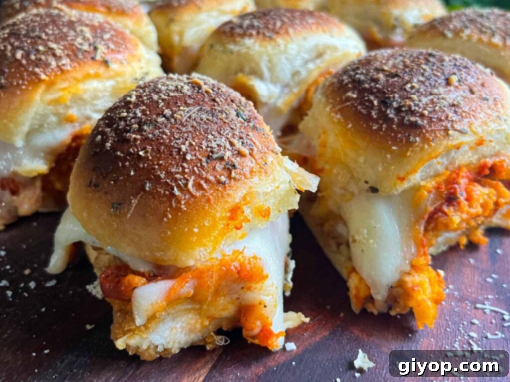 Cheesy Baked Chicken Parmesan Sliders 18 An array of chicken parmesan sliders garnished with fresh herbs on a wooden board, ready for guests.